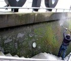 Strook’s Reverse Moss Graffiti Mural Emerges from a Wall of the STUK Arts Centre In Belgium