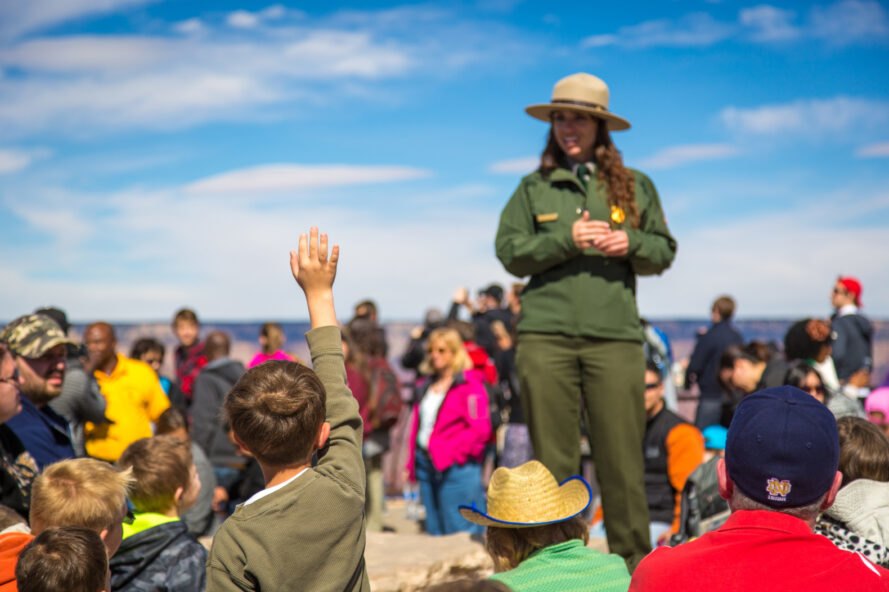 park ranger in green uniform provides numerous tourists with information