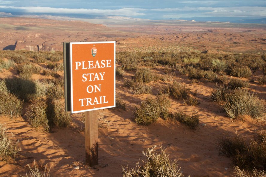 a sign at Horseshoe Bend says please stay on trail with large open land