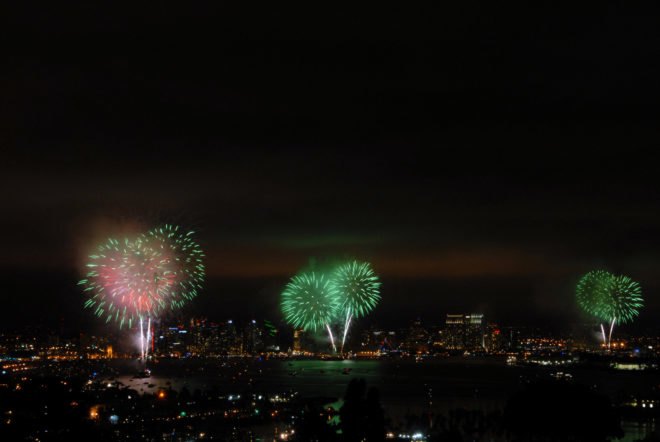 Green fireworks exploding in the sky above a city