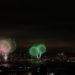 Green fireworks exploding in the sky above a city