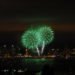 Green fireworks exploding in the sky above a city