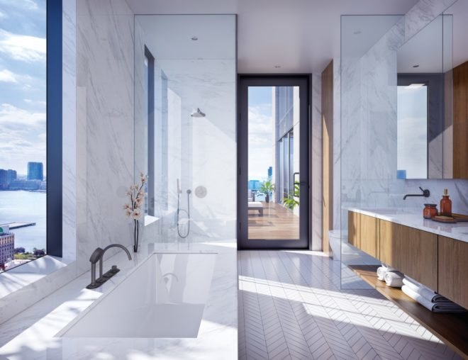 The bathroom features white herringbone flooring, a large bathtub, a separate shower with glass walls, and a long vanity with wood cabinets. The bathroom also has large windows.