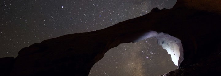 A natural arch formation against a starry sky