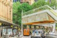 Cars and buses drive underneath housing units.