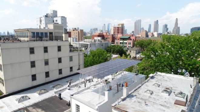 Solar panels are raised above a NYC rooftop.