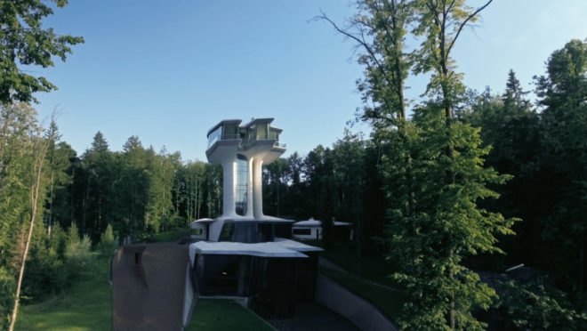 The home is built into a grassy slope and surrounded by trees.