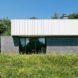 The exterior of the cabin, which has three gray concrete cubic volumes topped with a white metal box for the roof.