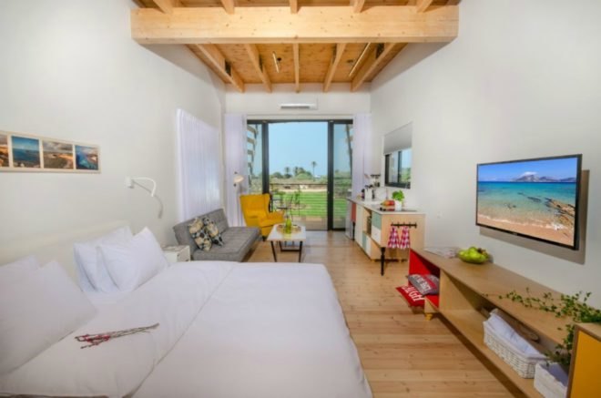 In the studio layout, the living space flows into the bedroom area, which has a bed and wall-mounted television.