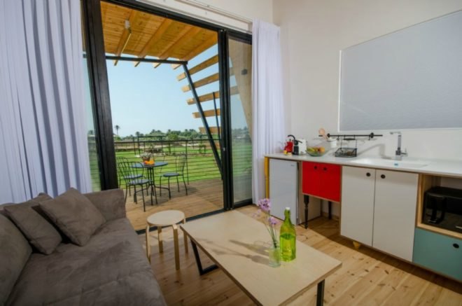 Across the gray sofa is a kitchen space, with counters, colorful cabinets, a microwave, and sink.