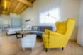 Inside, a bright yellow chair is next to a couch. In this studio style bungalow, a bed is next to the sofa.