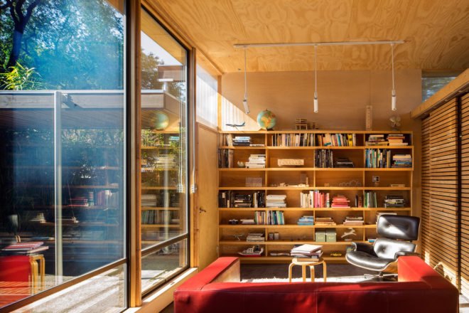 In front of the red love seat is a large bookshelf, which occupies one wall of the studio.