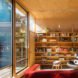 In front of the red love seat is a large bookshelf, which occupies one wall of the studio.