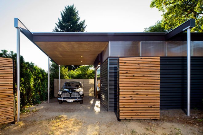 A dark vintage car is parked under the overhang.