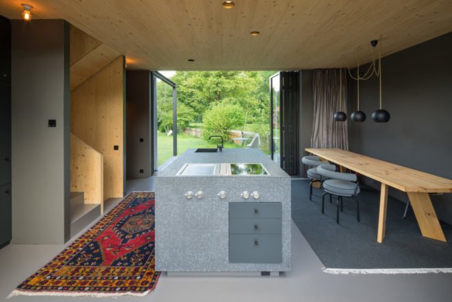 interior features kitchen island, long wood dining table and bright colored rug