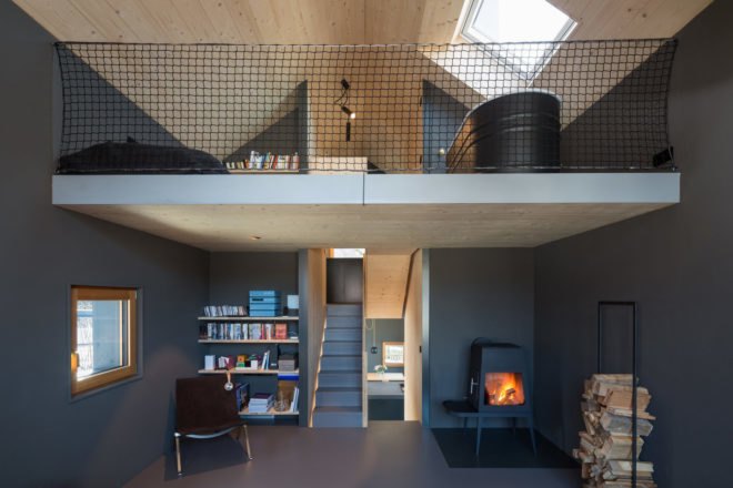 downstairs, a bookshelf, fireplace, and a chair; upstairs, a bathtub and another bookshelf