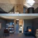 downstairs, a bookshelf, fireplace, and a chair; upstairs, a bathtub and another bookshelf