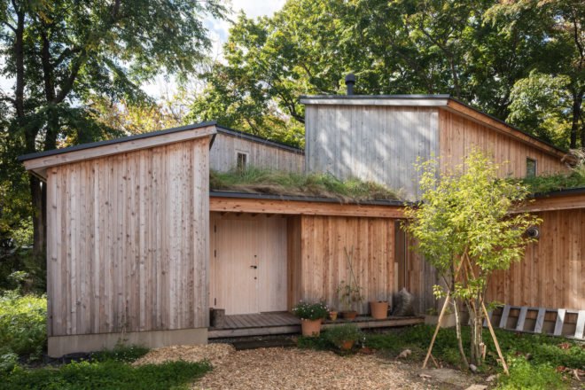 A small garden area in front of a cabin with green roofs.