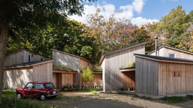 A cluster of wooden cabins in front of blossoming trees.