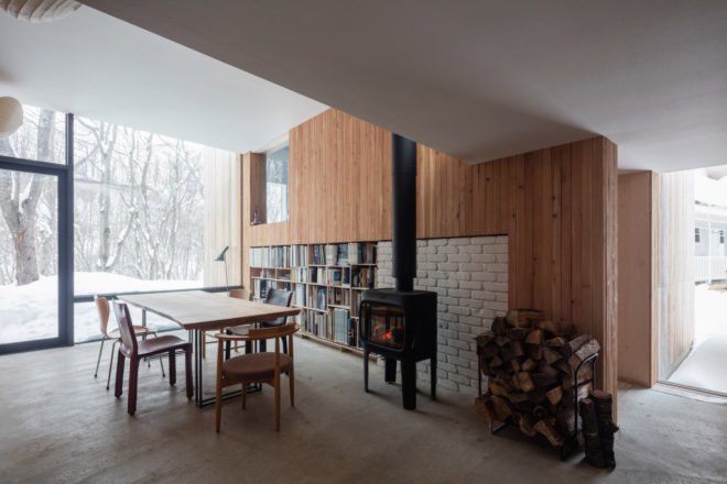 A meeting room with a table, chairs, a bookshelf, and a wall-length window.