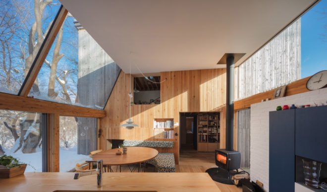 A living room with a glass wall, a table, and couches.