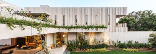 Exterior image of the stone home which is filled with green plants.