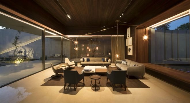 One interior room features two neutral toned couches and four chairs with a large table in the middle. The couches and chairs are arranged in a square.