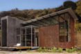 The home has large glass windows and is clad in copper and concrete