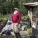 A citizen of McCarthy Alaska stands in front of his rustic home