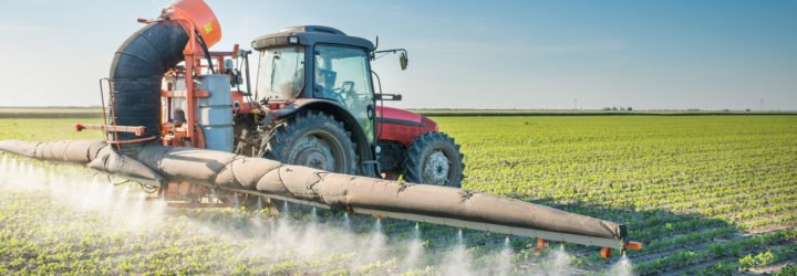 tractor spraying pesticides on soy bean
