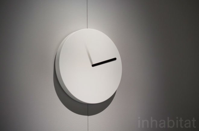 Sundial clock by YOY is a round, white clock with one black bar and one faded gray bar.