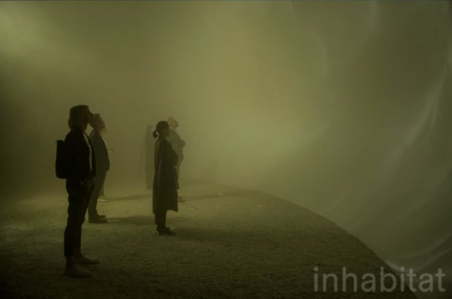 People stand inside the installment, looking at the curved walls of the dome.