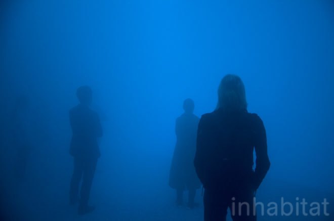 People stand in the blue light of the mist-filled dome.