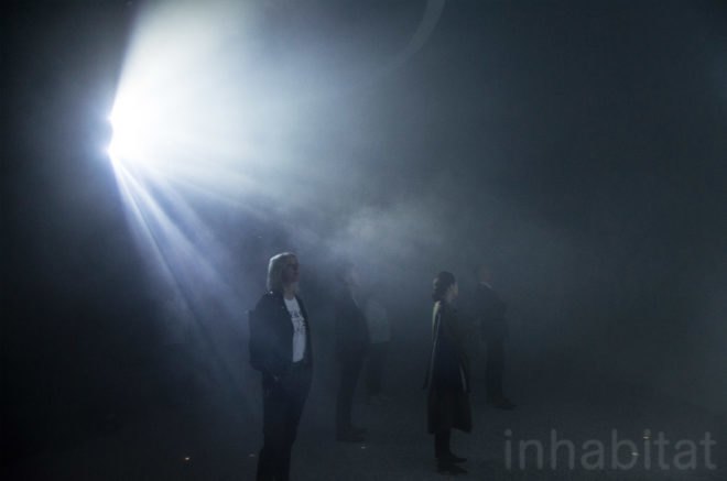 People stand under a spotlight inside the installment.
