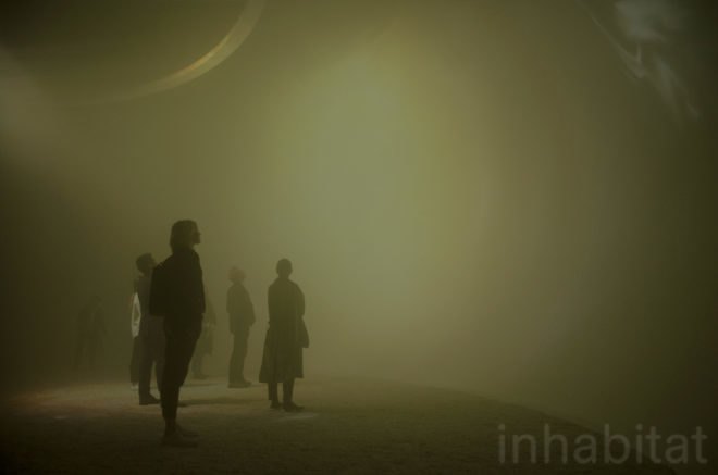 People stand inside the installment, looking at the curved walls of the dome.
