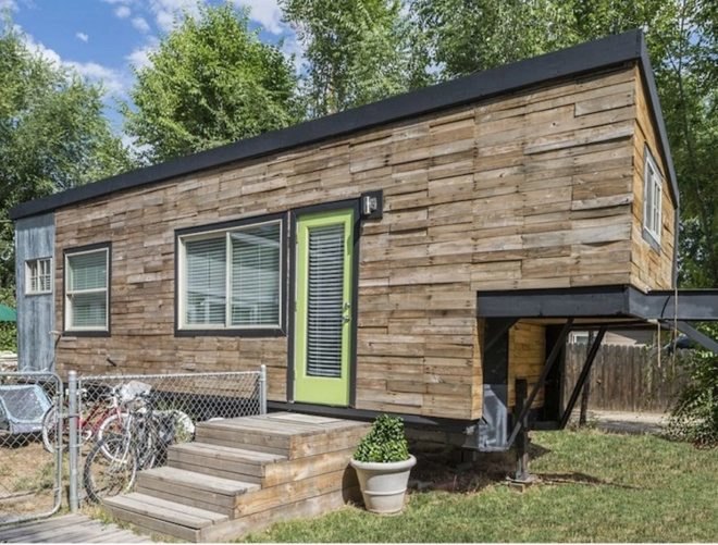 A tiny home with wooden siding and a bright green door.