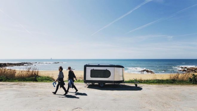 The Tipoon Travel Machine against a beach and ocean backdrop.