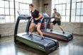 Two people use the sustainable treadmills.