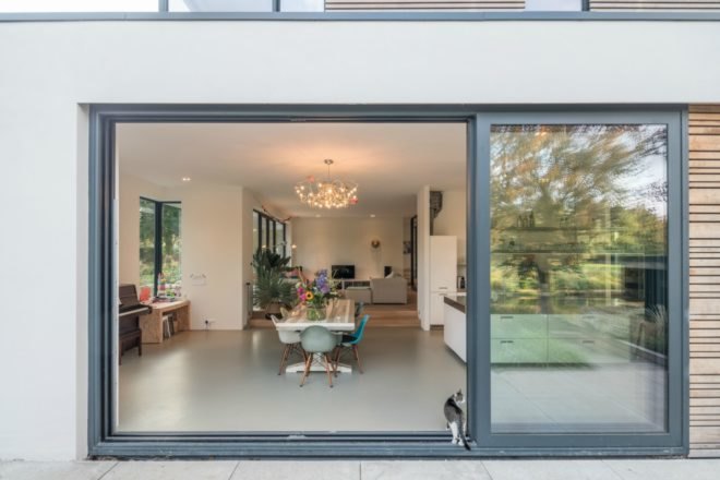 A cat is entering the home through the large sliding glass patio door. This image is from the patio looking into the dining space.