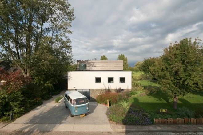 Exterior view of the house, shows the driveway and a vintage blue Volkswagen.