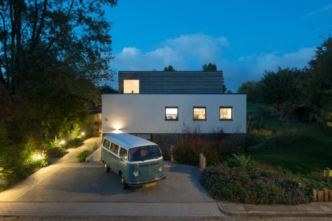 Lights illuminate the sidewalk leading up to the house from the driveway.