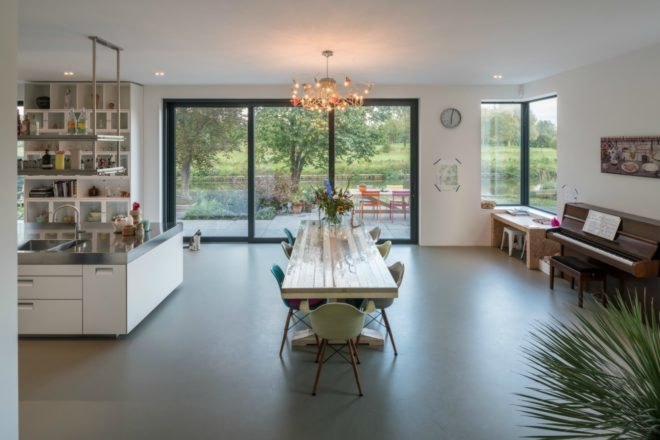 Next to the indoor dining space is a wooden piano against the wall. On the opposite side is the kitchen island.
