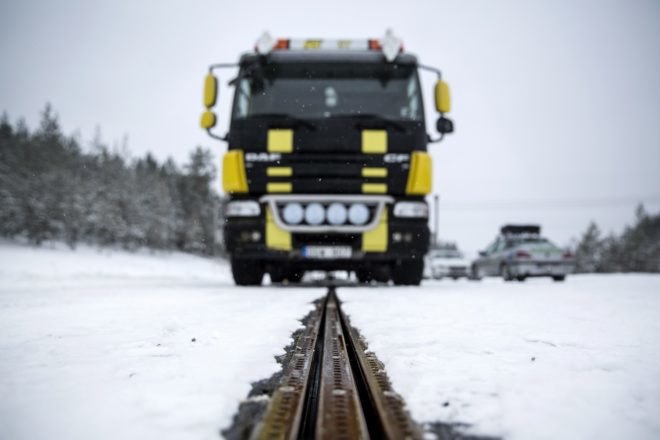 An electric truck drives down a snow-covered electrified road that charges the vehicle as it drives.