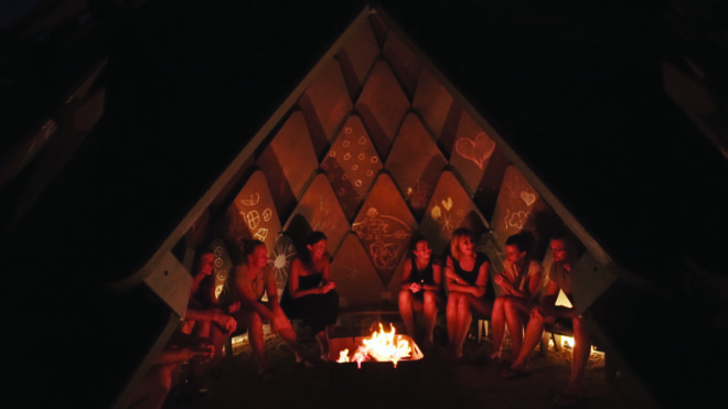 group of friends gathered around a campfire inside the pinecone-like structure