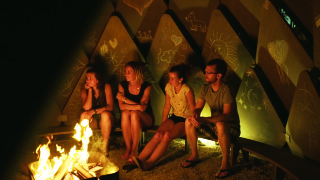 four people illuminated by the campfire