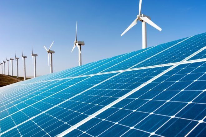 Wind turbines and solar panels against a blue sky