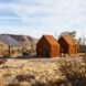 pair of rusted steel clad cabins in the desert