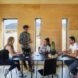 four people sitting at a table inside a wooden cabin