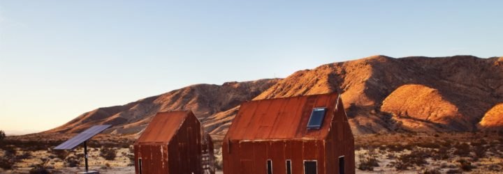 pair of rusted steel clad cabins in the desert