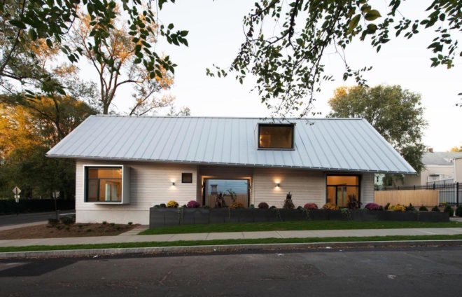 A side view of a prefab home and its gray standing seam roof